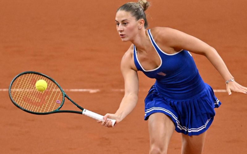 Tenisistka Marta Kostiuk uderza piłkę rakietą podczas meczu na kortach ziemnych.